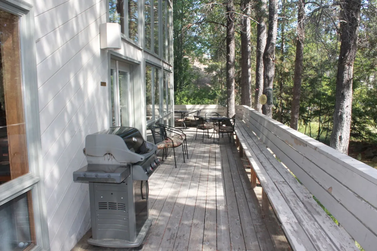 The outdoor deck with a grill, seating, and surrounding trees. The setup is ideal for barbecues, gatherings, or simply enjoying the outdoors, seamlessly extending the living space outside.
