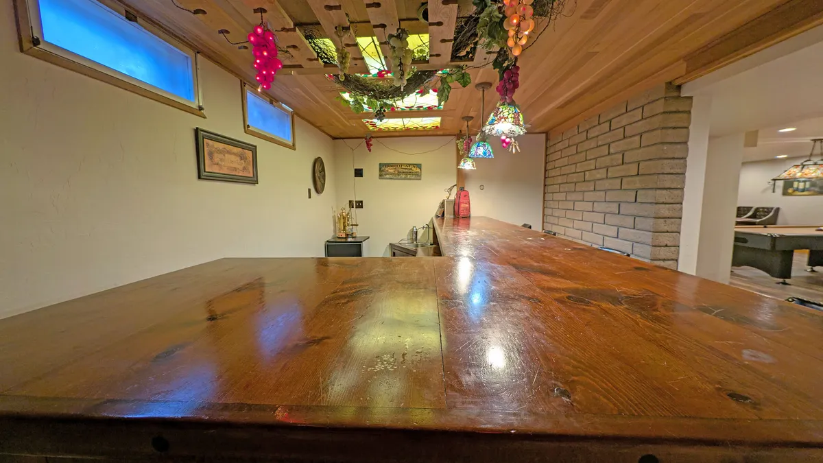 A stylish wooden bar top is adorned with stained glass ceiling fixtures and decorative grape vines, creating an inviting atmosphere perfect for group gatherings, toasts, and celebrations.