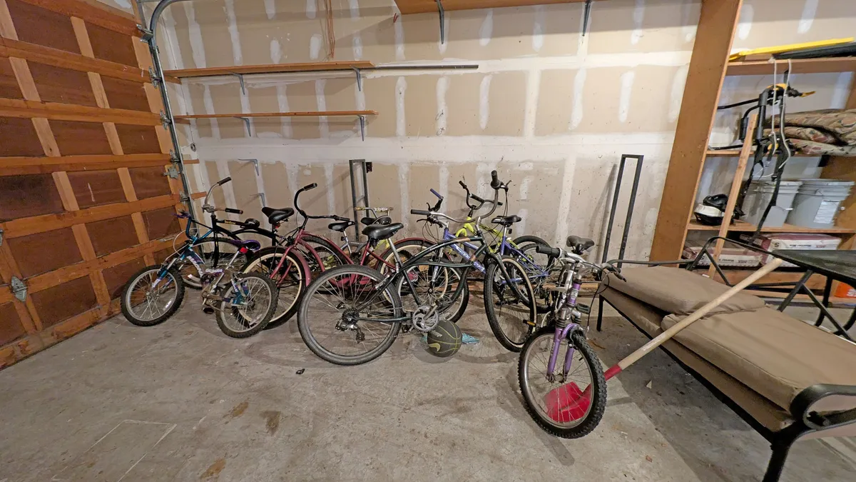 A garage or storage area with several bicycles lined up, shelves stocked with gear, and a small seating area, evoking adventure and family fun. The image suggests easy access to bikes for guest use, as described in the section.
