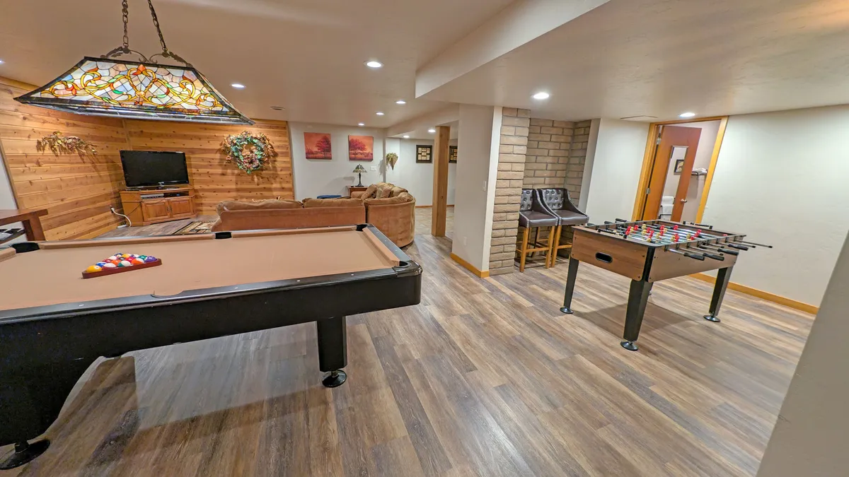 A vibrant game zone comes alive in this shot, featuring a pool table and a foosball table beneath a stained glass light fixture. The inviting seating area close by ensures everyone can join the fun, whether playing or socializing. The mood is playful and relaxed, echoing the energy of group gatherings and friendly competitions.