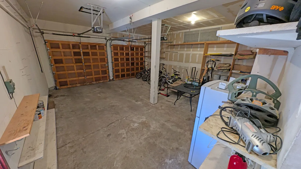 This image showcases a garage space with visible bicycles, workbench, and tools, highlighting practical amenities for active families preparing for biking adventures. The presence of bikes directly connects to the home's offer of bike use and outdoor exploration.